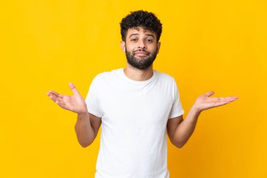 Young Moroccan man isolated on yellow background making doubts gesture