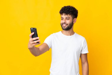 Young Moroccan man isolated on yellow background making a selfie
