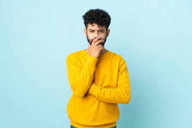 Faslı genç bir adam mavi arka planda izole edilmiş.