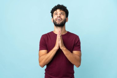 Mavi arka planda izole genç Faslı adam avuç içini bir arada tutuyor. İnsan bir şey ister.