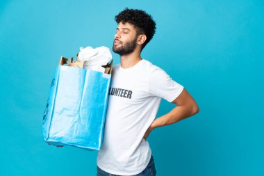 Young Moroccan man holding a recycling bag full of paper to recycle over isolated background suffering from backache for having made an effort