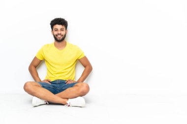 Young Moroccan handsome man sitting on the floor over isolated background laughing