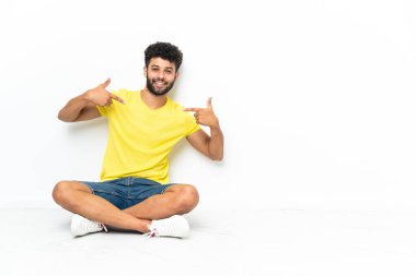 Young Moroccan handsome man sitting on the floor over isolated background proud and self-satisfied
