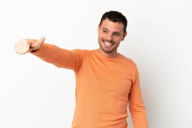 İzole edilmiş beyaz arka planda Brezilyalı bir adam baş parmak hareketi yapıyor.