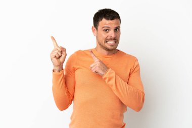 Brazilian man over isolated white background frightened and pointing to the side