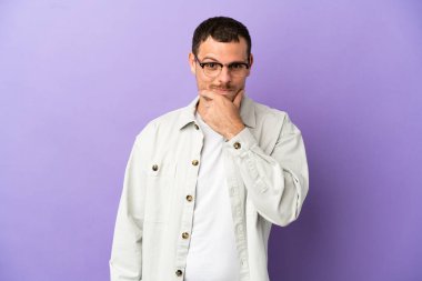 Brazilian man over isolated purple background thinking
