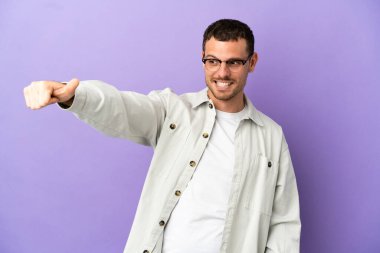 Mor arka planda kalan Brezilyalı bir adam baş parmak hareketi yapıyor.