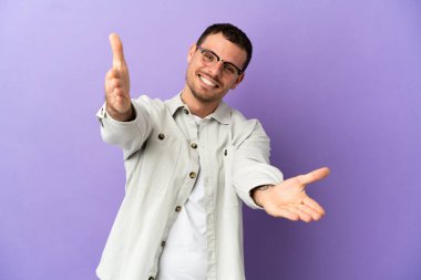 Brazilian man over isolated purple background presenting and inviting to come with hand