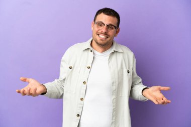 Brazilian man over isolated purple background happy and smiling