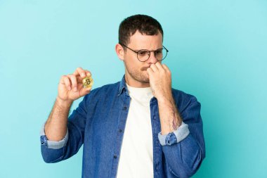 Brezilya 'lı adamın Bitcoin' i izole edilmiş mavi arka planda tutması şüphe uyandırıyor