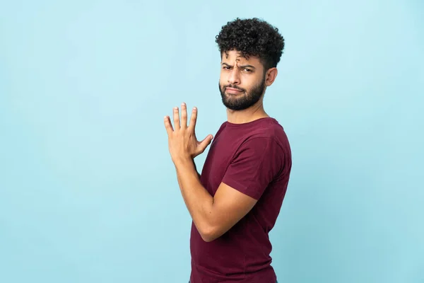 Young Moroccan man isolated on blue background scheming something