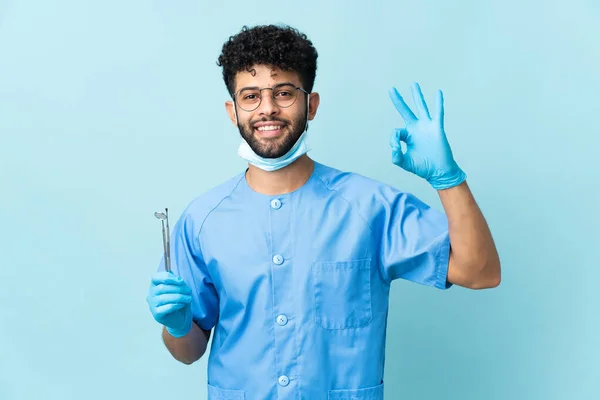 Moroccan Dentist Man Holding Tools Isolated Blue Background Showing Sign — стоковое фото