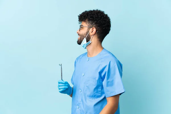 Moroccan Dentist Man Holding Tools Isolated Blue Background Laughing Lateral — Fotografia de Stock