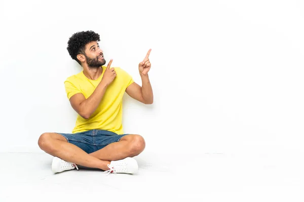 Young Moroccan Handsome Man Sitting Floor Isolated Background Pointing Index — Stockfoto