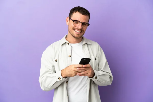 Brazilian Man Isolated Purple Background Sending Message Mobile — Stockfoto