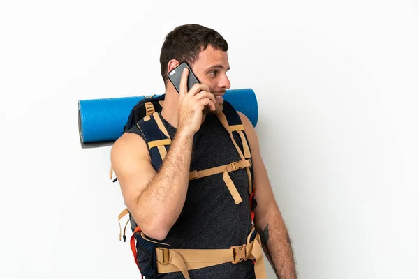 隔離された白い背景の上に大きなリュックを持つブラジルの登山家の男誰かと携帯電話との会話を保つ — ストック写真
