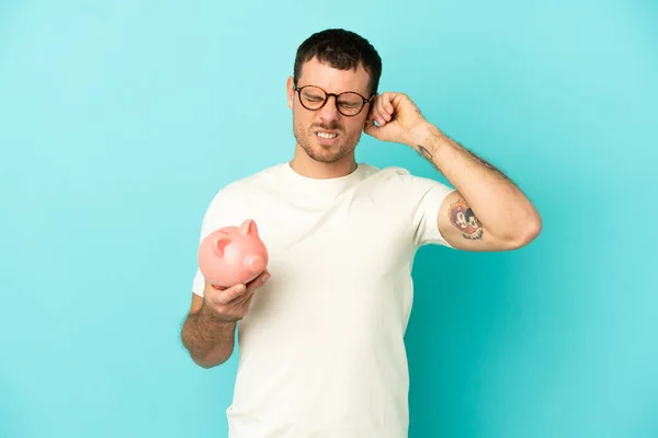 Brazilian Man Holding Piggybank Isolated Blue Background Frustrated Covering Ears — Stock fotografie