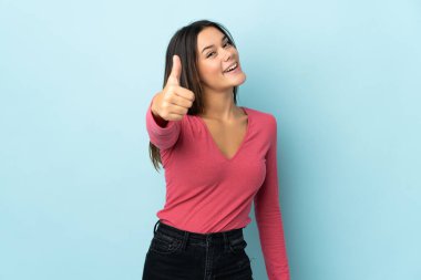 Teenager girl isolated on blue background with thumbs up because something good has happened