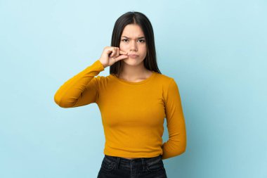 Teenager girl isolated on blue background showing a sign of silence gesture