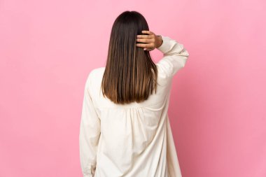 Teenager girl isolated on pink background in back position and thinking