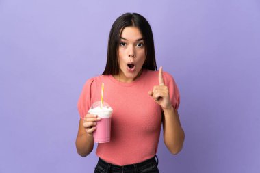 Elinde çilekli milkshake tutan genç kız çözümü bulmak için parmağını kaldırıyor.