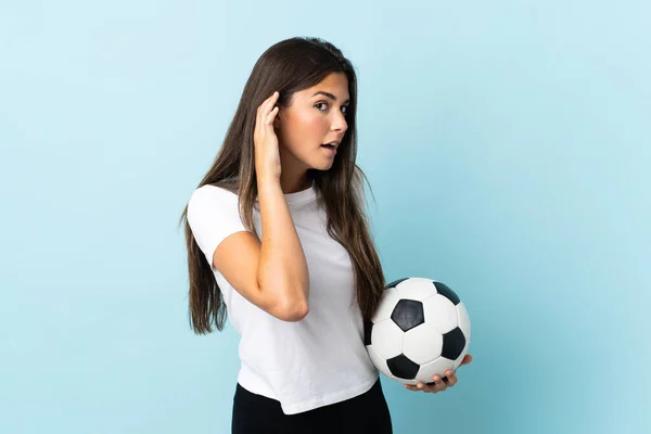 Young Football Player Brazilian Girl Isolated Blue Background Listening Something — Zdjęcie stockowe