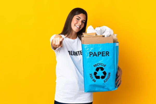 若いブラジル人の女の子は幸せな表情で前を向いて黄色の背景に隔離されたリサイクル紙の袋の完全な保持 — ストック写真