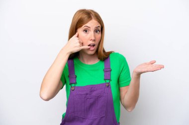 Beyaz arka planda izole edilmiş genç, kızıl saçlı bir kadın telefon hareketinde bulunuyor.