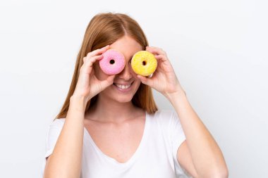 Genç kızıl saçlı kadın, beyaz arka planda izole edilmiş gözlerinde donutlarla.