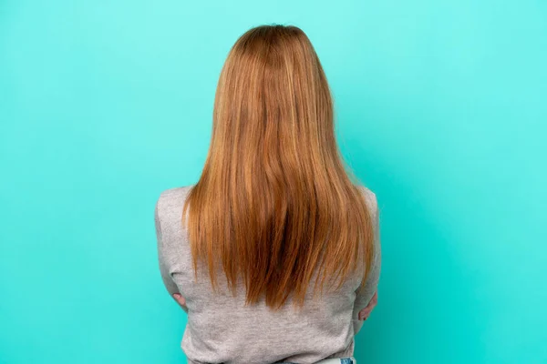年轻的红头发女人 背向蓝色背景 被隔离 — 图库照片
