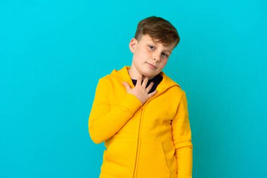 Küçük kızıl saçlı çocuk mavi arka planda izole edilmiş gülümserken yukarı bakıyor