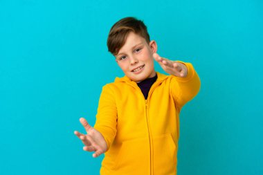 Mavi arka planda izole edilmiş küçük kızıl çocuk sunar ve davet eder.