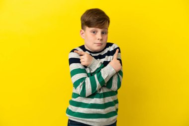 Sarı arka planda izole edilmiş küçük kızıl saçlı çocuk, yan taraftakilerin şüpheleri olduğunu gösteriyor.