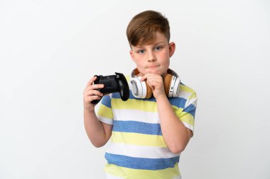 Küçük kızıl saçlı çocuk beyaz arka planda izole edilmiş bir oyun sahası tutuyor. Şüpheleri var ve düşünüyor.