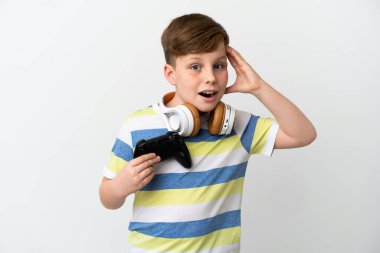 Küçük kızıl saçlı çocuk beyaz arka planda sürpriz bir ifadeyle izole edilmiş bir oyun tahtası tutuyor.