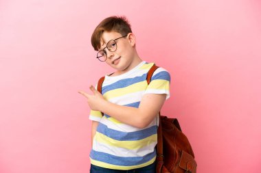 Küçük kızıl saçlı beyaz çocuk pembe arka planda izole edilmiş.
