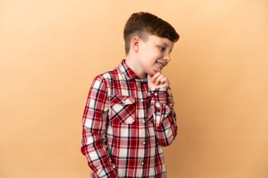 Bej arka planda izole edilmiş kızıl saçlı çocuk.