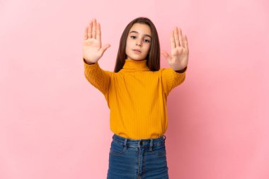 Pembe arka planda izole edilmiş küçük bir kız dur hareketi yapıyor ve hayal kırıklığına uğruyor