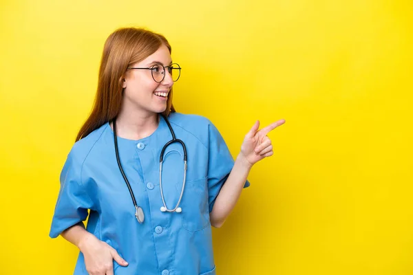 Junge Rothaarige Krankenschwester Isoliert Auf Gelbem Hintergrund Zeigt Mit Dem — Stockfoto