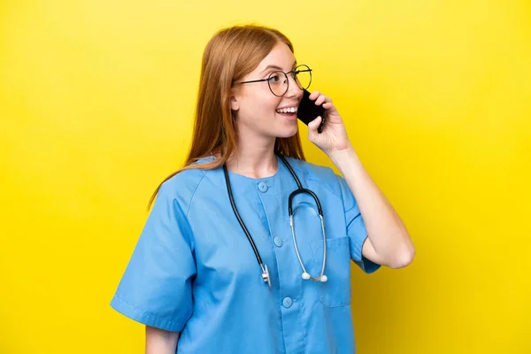 Joven Enfermera Pelirroja Aislada Sobre Fondo Amarillo Manteniendo Una Conversación —  Fotos de Stock