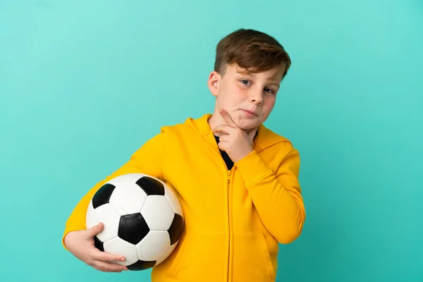 Roodharige Kind Spelen Voetbal Geïsoleerd Blauwe Achtergrond Met Twijfels — Stockfoto