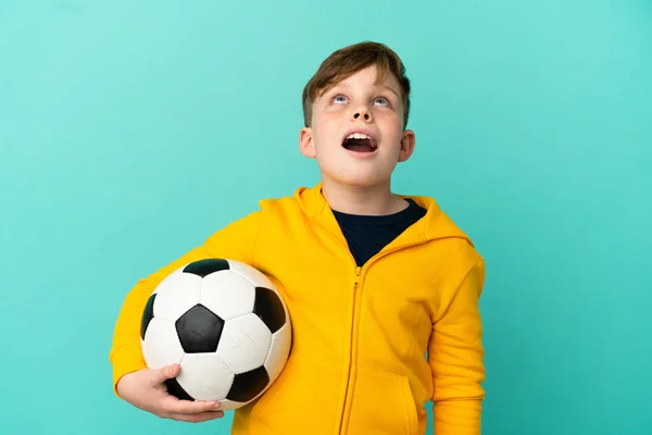 Roodharige Kind Spelen Voetbal Geïsoleerd Blauwe Achtergrond Zoek Naar Omhoog — Stockfoto