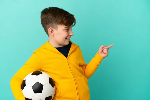Roodharige Kind Spelen Voetbal Geïsoleerd Blauwe Achtergrond Wijzend Vinger Naar — Stockfoto