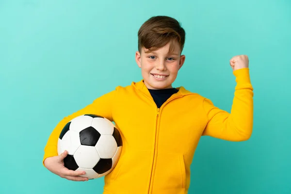 Redhead Παιδί Παίζει Ποδόσφαιρο Απομονωμένο Μπλε Φόντο Γιορτάζει Μια Νίκη — Φωτογραφία Αρχείου