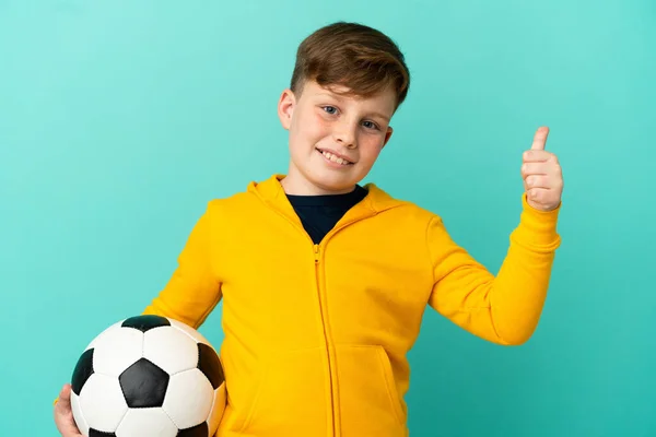 Kleine Roodharige Jongen Geïsoleerd Blauwe Achtergrond Met Voetbal Met Duim — Stockfoto