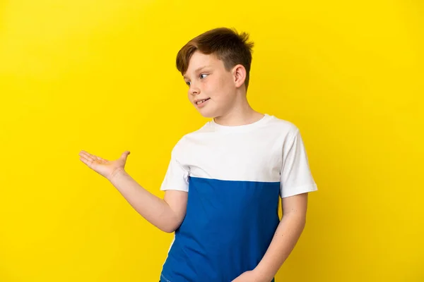 Μικρό Κοκκινομάλλικο Αγόρι Απομονωμένο Κίτρινο Φόντο Παρουσιάζοντας Μια Ιδέα Ενώ — Φωτογραφία Αρχείου