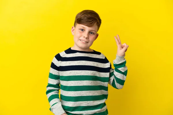 Pequeno Menino Ruivo Isolado Fundo Amarelo Sorrindo Mostrando Sinal Vitória — Fotografia de Stock