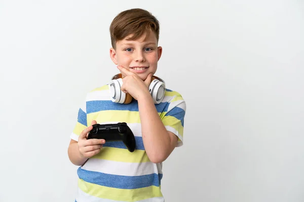 一个红头发的小男孩拿着一个因白色背景而被隔离的游戏垫 开心地微笑着 — 图库照片