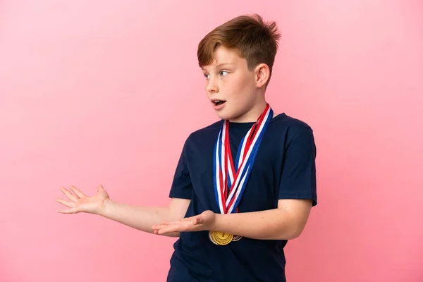 Pequeño Pelirrojo Con Medallas Aisladas Sobre Fondo Rosa Con Expresión —  Fotos de Stock