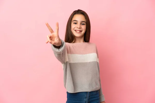 Klein Meisje Geïsoleerd Roze Achtergrond Glimlachen Tonen Overwinning Teken — Stockfoto